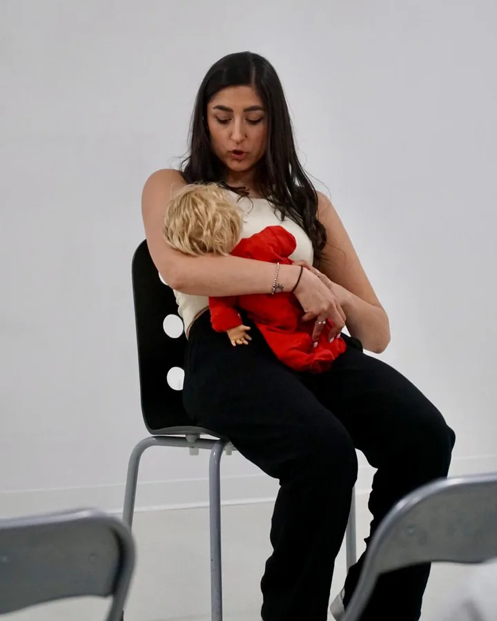 Ana mostra con un bambolotto come tenere il neonato durante un incontro di preparazione all'allattamento